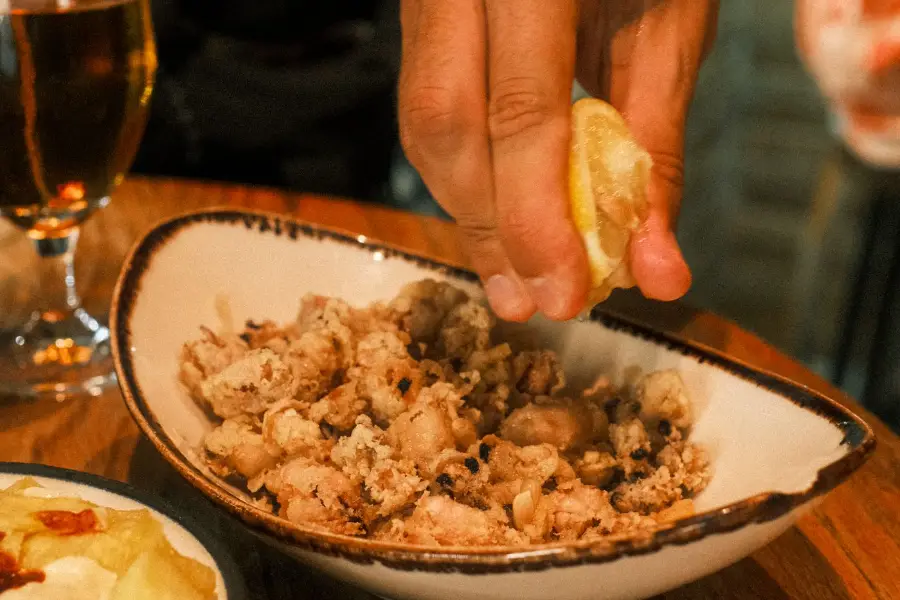 Alguien exprime limón sobre un plato, con una caña al lado
