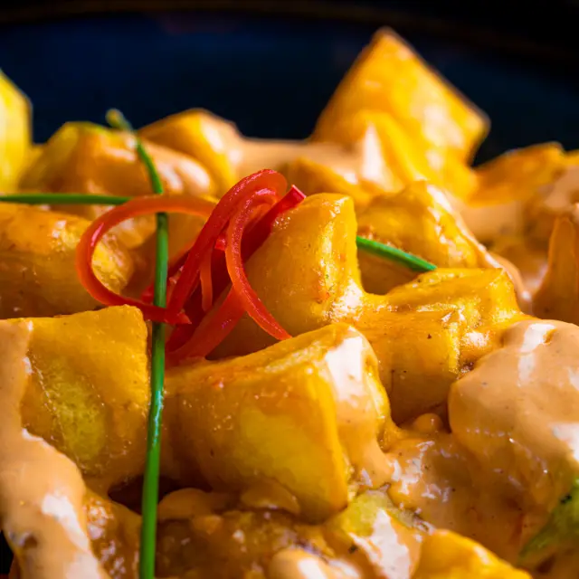Ración de patatas bravas con salsa brava y cebollino